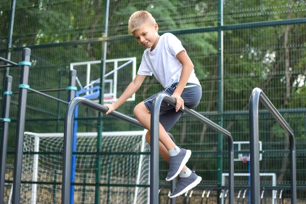 Chico en deportes callejeros hace ejercicios de gimnasia. Ciudad campo de deportes al aire libre. — Foto de Stock