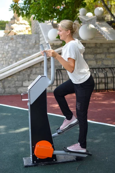 Mulher no parque infantil ao ar livre. mulher fazendo exercícios de ginástica no ginásio ao ar livre. — Fotografia de Stock