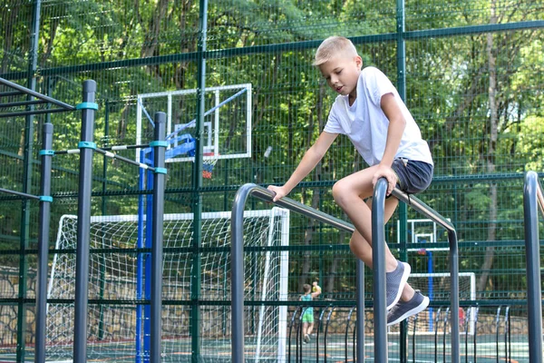 Niño atleta en campo de deportes al aire libre. Niño niño está ejercitando en el patio de recreo. — Foto de Stock