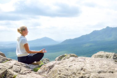 Genç bir kadın doğada rahatça oturur. Açık hava eğlencesi. Doğada meditasyon.
