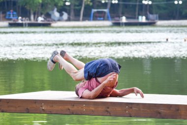 Yaşlı bir adam gölde yoga yapıyor. Bir emeklinin sağlıklı yaşam tarzı.