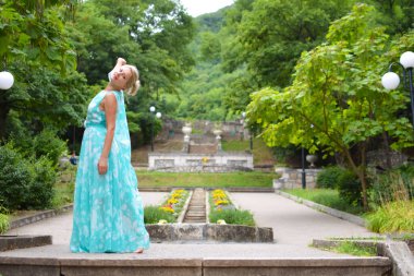 Yazın şehir parkında elbise giymiş güzel bir genç kadın..