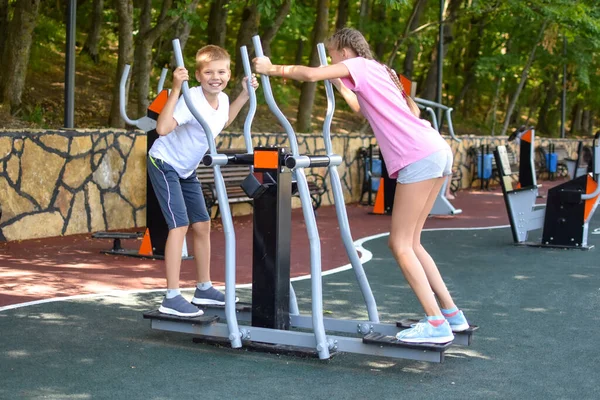 Дети подростки на спортивной площадке. Активные дети на спортивном тренажере. — стоковое фото