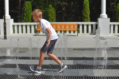 Çocuk sokak çeşmesinde eğleniyor. Parkta yaz çocuk oyunları.