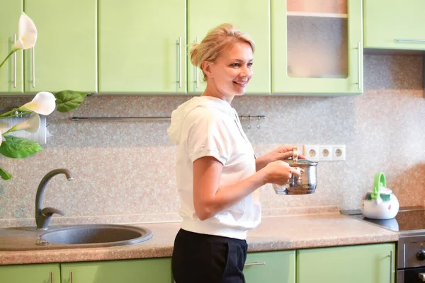 Mujer cocina en la acogedora cocina en casa. ama de casa prepara la cena en una cacerola — Foto de Stock