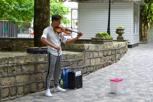 Уличный музыкант играет на скрипке. Городской парк с бесплатным музыкантом. — стоковое фото