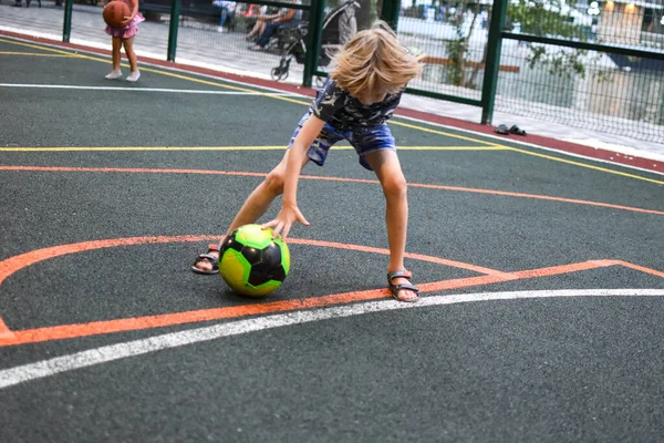 少年は遊び場でサッカーをします。スポーツ活動中の子供 — ストック写真