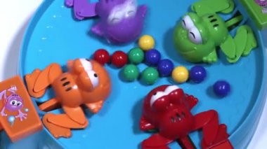 Dört aç plastik kurbağaların renkli topları ile besleme. Çocuk oyunu top toplama hızı.