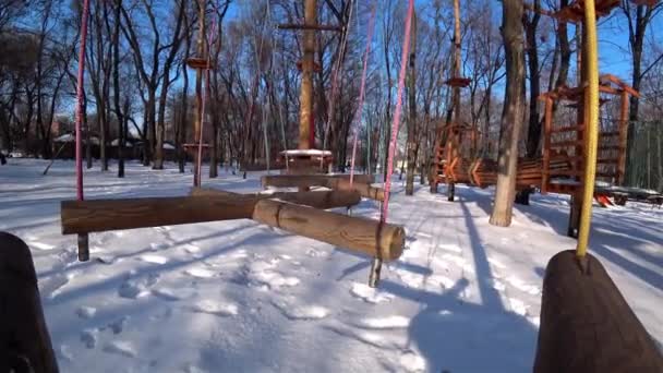 晴れた冬の日に都市公園における空の木製の幼児スイング — ストック動画
