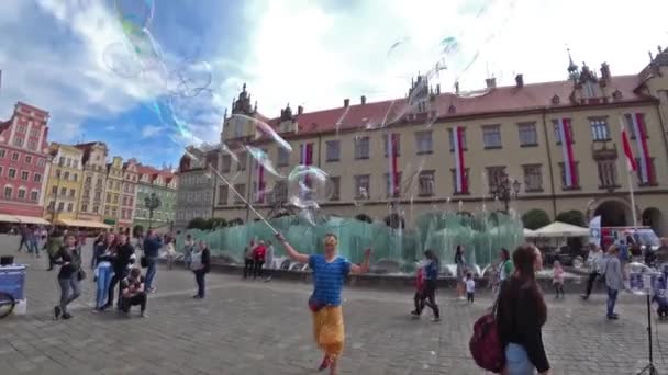 A man launches huge soap bubbles entertain tourists in the old city center. Wide angle, slow motion. — Stock Video