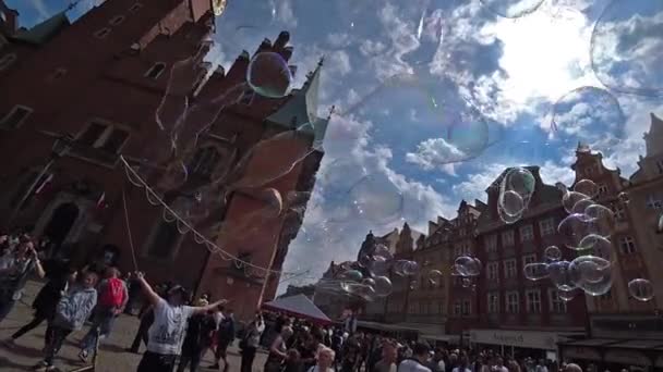 Mies lanseeraa suuria saippuakuplia viihdyttää turisteja vanhan kaupungin keskustassa. Laaja kulma, hidastus . — kuvapankkivideo