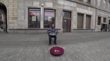 Sokak sanatçı genç hippi adam gerçekleştirme Street Play On bir askıda üzerinde davul.