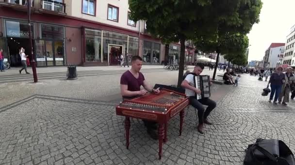 Уличные художники Молодые люди, выступающие на улице, играют веселую музыку на цимбаломе и аккордеоне — стоковое видео