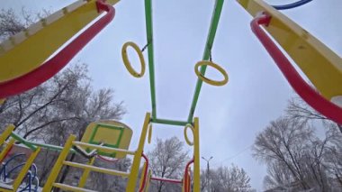 Çocuk salıncaklar Şehir Parkı bir oyun alanı üzerinde güneşli kış gününde boş, altından görüntülemek, aydınlatma.