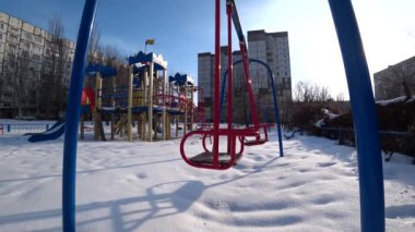 Çocuk salıncaklar Şehir Parkı bir oyun alanı üzerinde güneşli kış gününde boş, profil alt, arka ışık, geniş açı, 4 k.