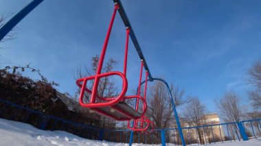 Çocuk salıncaklar Şehir Parkı bir oyun alanı üzerinde güneşli kış gününde boş, geniş açı, 4 k altından göster.