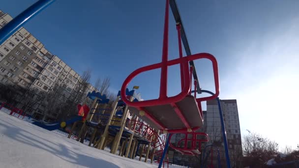 晴れた冬の日に都市公園における遊び場で子供たちのスイングを空 ボトム バックライト 広角からの眺め — ストック動画