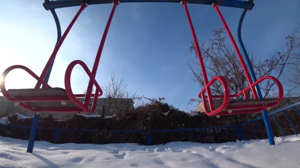 晴れた冬の日に都市公園における遊び場で子供たちのスイングを空 ボトム バックライト 広角からの眺め — ストック動画