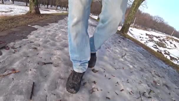 Man, klädd i blå jeans promenader i snön på en vinterdag. — Stockvideo