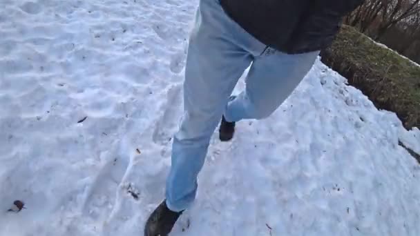 Man gekleed in blauwe jeans loopt in de sneeuw op een winterdag. — Stockvideo