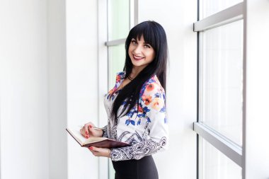 Genç güzel iş kadını ayakta pencerenin yanında, yazma 