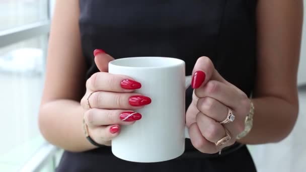 魅力的な若い女性 窓の近くに立っている 白いカップからお茶やコーヒーを飲む — ストック動画