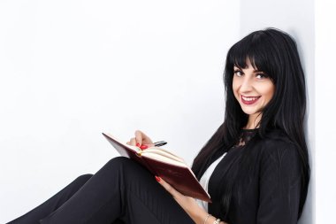 Bir defter tutan genç güzel mutlu esmer kadın giyinmiş 