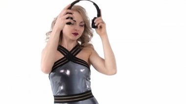 Lateks mayo giymiş genç çekici sarışın kadın portre siyah kablosuz kulaklıklar ve dans romantik müzik dinleyin. Yavaş hareket, beyaz arka planda izole.