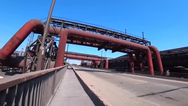 A man walks on the road through the industrial zone past huge pipes. Concept industrial tourism — Stock Video