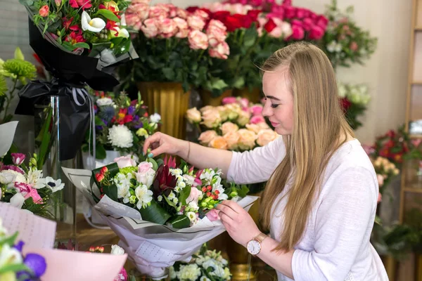 Usmívající se mladá květinářství, která dělá krásnou kytici růží — Stock fotografie
