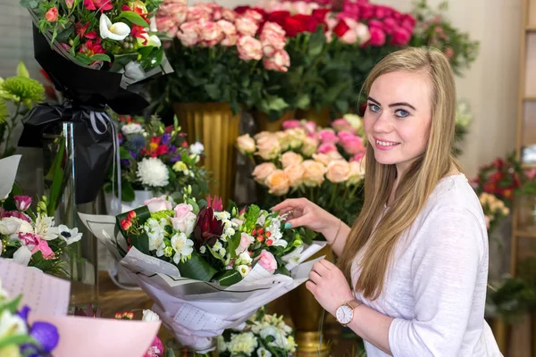 Usmívající se mladá květinářství, držící krásnou kytici růží — Stock fotografie