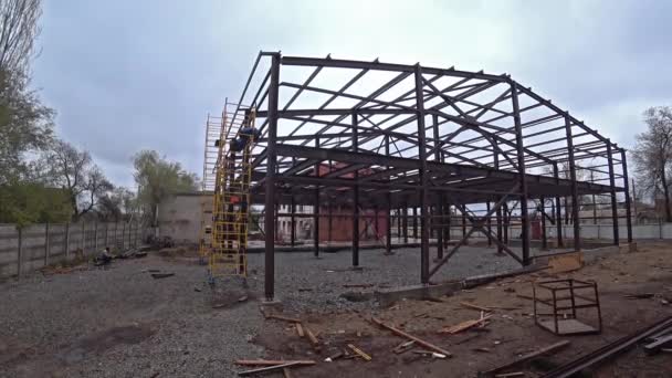 Man lasser werken aan de bouw van een gebouw van metalen balken. — Stockvideo