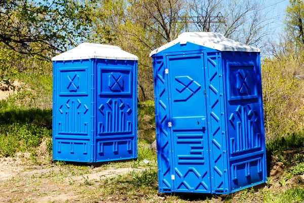 Dos cabinas azules de baños químicos en el parque en el soleado verano D — Foto de Stock