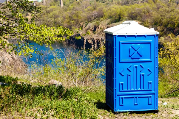 Blauwe cabine van chemisch toilet in een berg Park op de achterkant van de rivier — Stockfoto