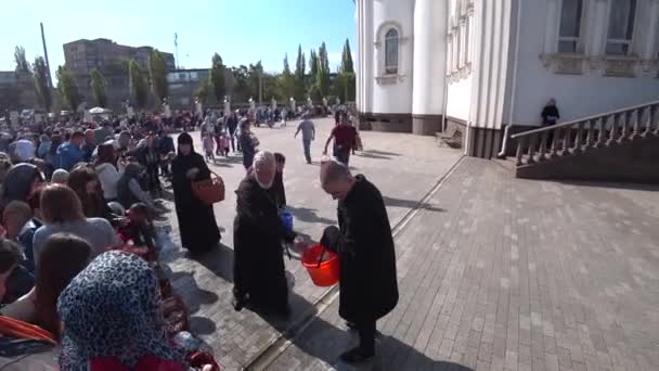 Kryvyi Rih, Oekraïne-april, 2019:. Mensen die Pasen vieren. Oekraïense orthodoxe priester zegent Pasen cakes en eieren door heilig water. — Stockvideo