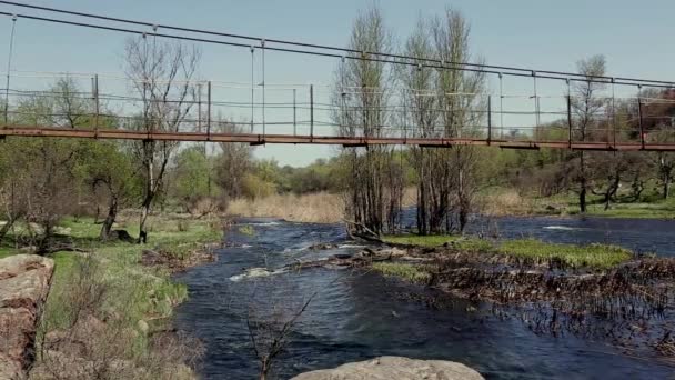 Vecchio ponte di metallo dall'altra parte del fiume in campagna il giorno soleggiato — Video Stock