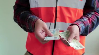 Yansıtıcı yelek giymiş adam işçi arap para dirhem saymak. Eller closeup açık yeşil arka planda izole.