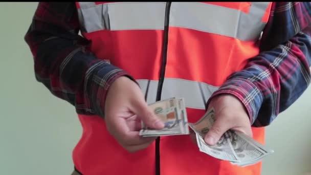 조끼를 노동자는 새로운 지폐를 계산하고 카메라에 제공합니다 배경에 클로즈업 — 비디오