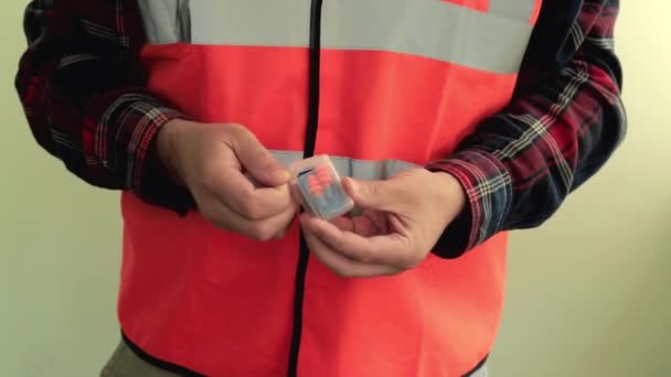Εργάτης Ντυμένος Αντανακλαστικό Γιλέκο Δίνει Στην Κάμερα Προστατευτικές Ωτοασπίδες Χέρια — Αρχείο Βίντεο