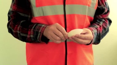 Yansıtıcı yelek giymiş adam elektrikçi kamera enerji tasarrufu Led lamba vermek. Eller closeup açık yeşil arka planda izole.