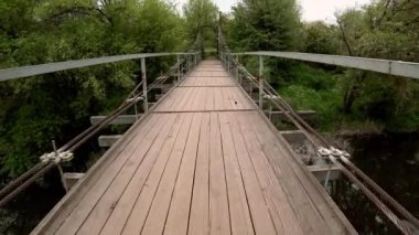 Bir parkta bir nehir üzerinde eski köprü üzerinde yürüyüş. Pov atış.