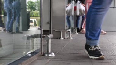 Berlin, Almanya - Mayıs, 2019: Alışveriş merkezini ziyaret eden birçok kişi alışveriş için cam kapıdan giriyor. Bacaklar yakın çekim, alt görünüm.