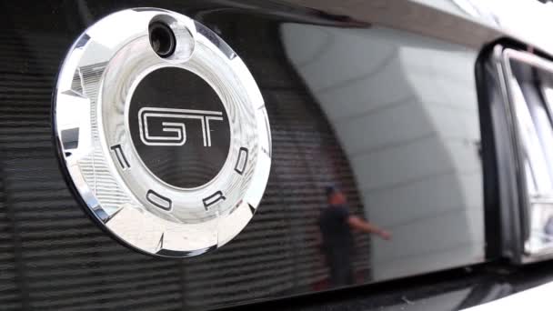 Logo Ford Mustang GT sur une voiture noire. Dans le reflet d'une voiture de luxe, les gens marchent . — Video