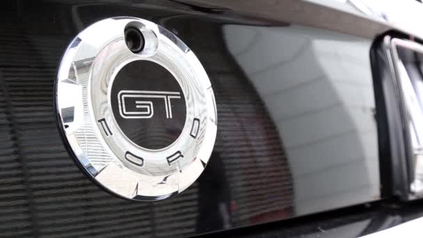 Siyah bir araba üzerinde Ford Mustang Gt logosu. Lüks bir arabanın yansıması olarak, insanlar yürümek. — Stok video