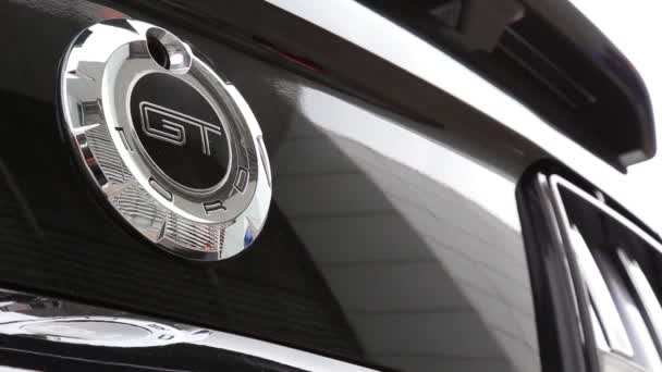 Logo Ford Mustang GT sur une voiture noire. Dans le reflet d'une voiture de luxe, les gens marchent . — Video