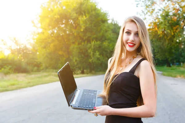 Joven mujer de negocios rubia hermosa con un ordenador portátil en un parque . —  Fotos de Stock