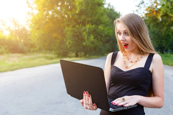 Una chica rubia extraña mira un portátil. Mujer gerente de trabajo — Foto de Stock