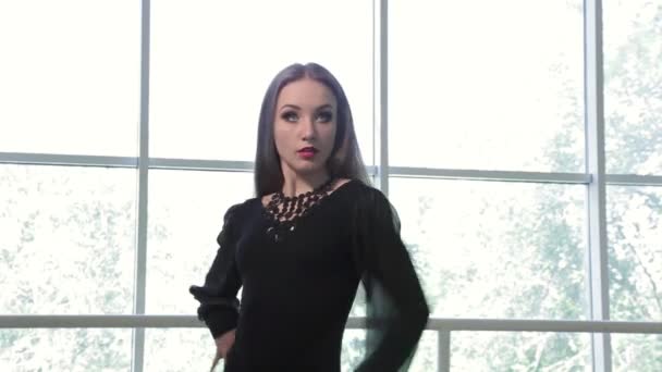 美丽的年轻黑发女人穿着黑色性感西装跳舞在工作室对大窗口 — 图库视频影像