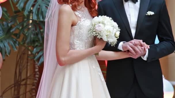新郎新婦が結婚式に手をつないでいる バラの花束を持つ白いドレスの女性 — ストック動画