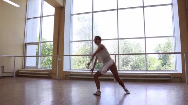 穿着白色衣服的年轻而瘦小的芭蕾舞演员在一个大窗户前跳舞 — 图库视频影像